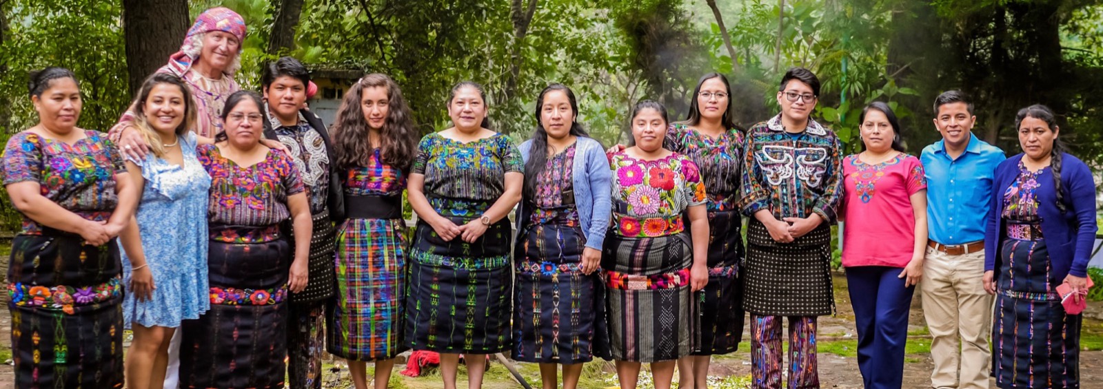 Das Team der Stiftung PAZ MUNDO in Guatemala, Frauen und Männer in Maya-Tracht und Alltagskleidung, in einer Reihe im Garten