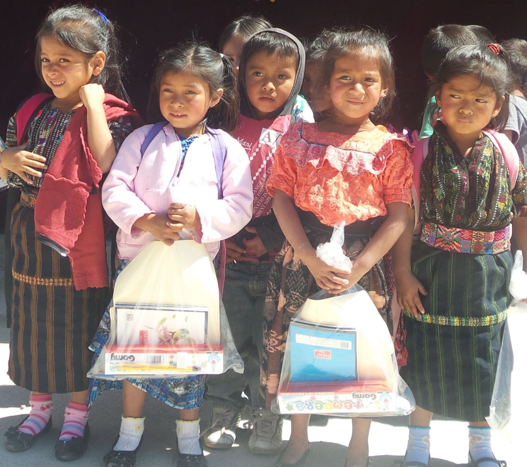 Maya-Kinder in Tracht mit ihren neuen Schulsachen in Tüten