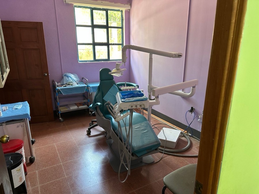 Behandlungszimmer der Zahnarztpraxis mit türkisfarbenem Behandlungsstuhl und lila Wänden